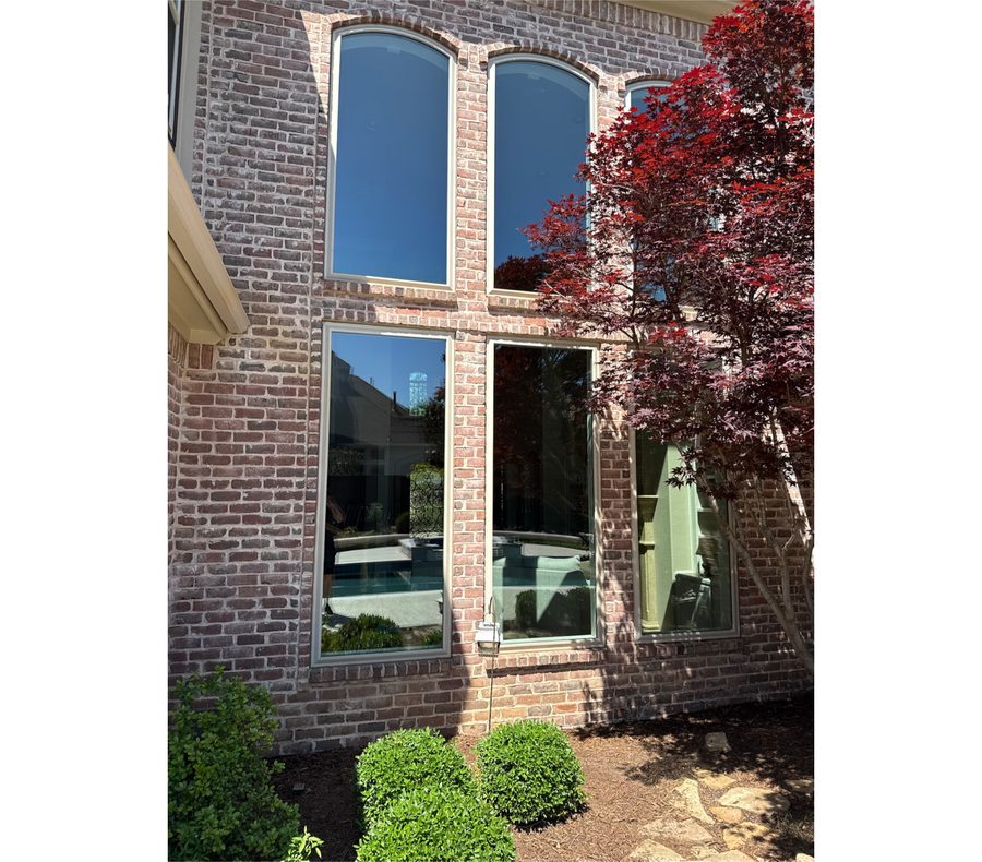 Two-story brick home with tall clean windows and a red maple