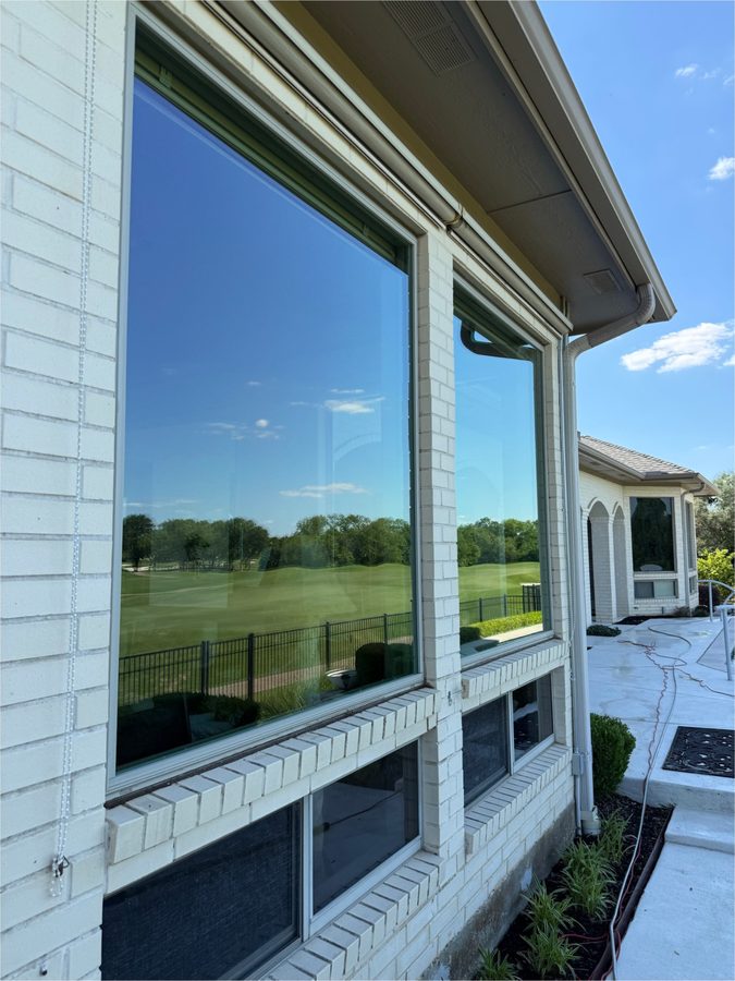 Large picture windows on a white brick home overlooking a golf course