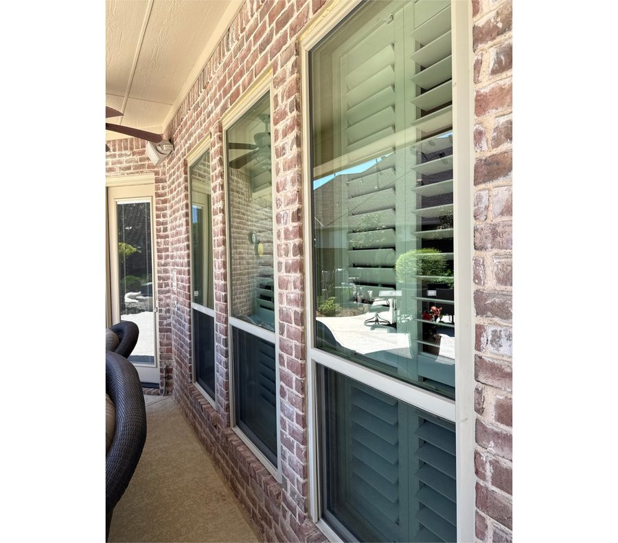 Tall clean windows with interior shutters along a covered patio
