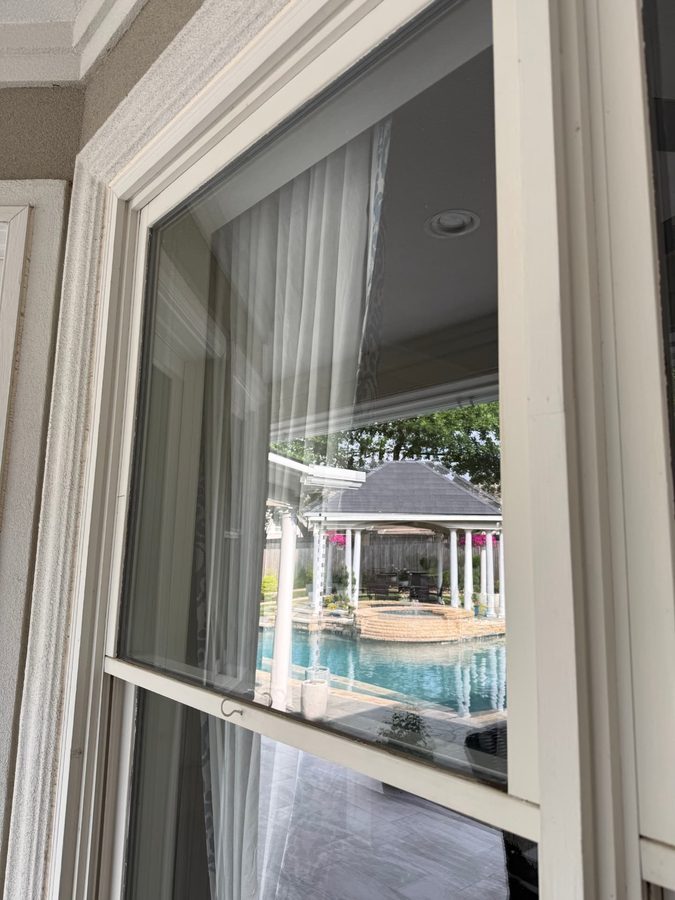 Clean double-hung window overlooking a pool and gazebo