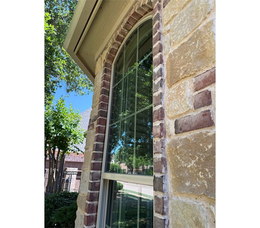 Close-up of an arched window with internal grids in brick and stone
