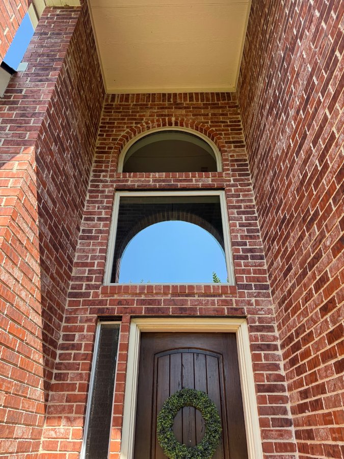 Two-story red brick entry with an arched accent window above the door
